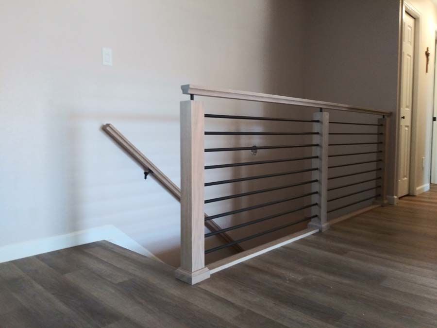 Wooden railing with horizontal bars, near doorway and wall; wood-look flooring.