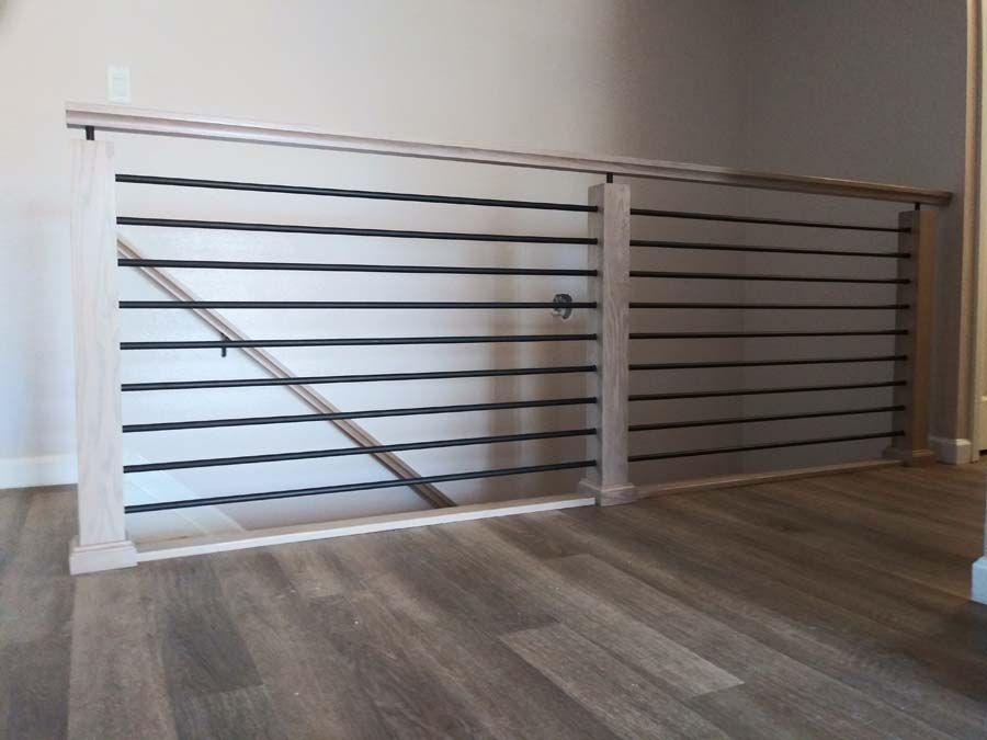 Light wood railing with black horizontal bars on a wood floor.