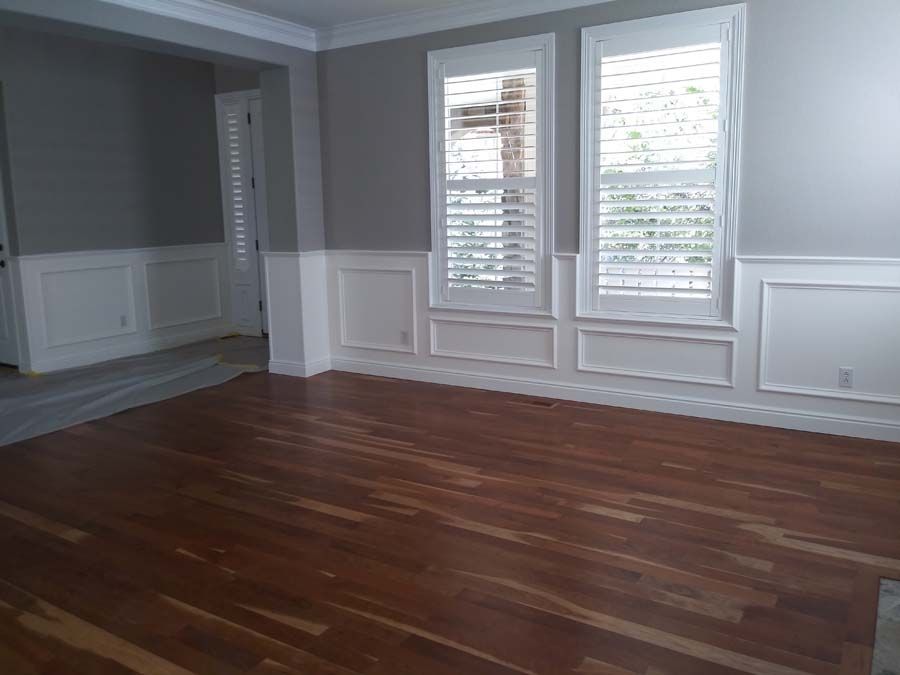 Empty room with hardwood floors, gray walls, white trim and shutters.
