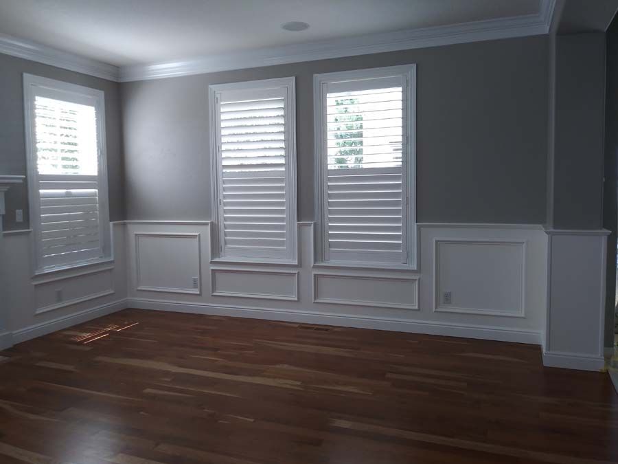 Empty room with hardwood floors, gray walls, white shutters and trim.