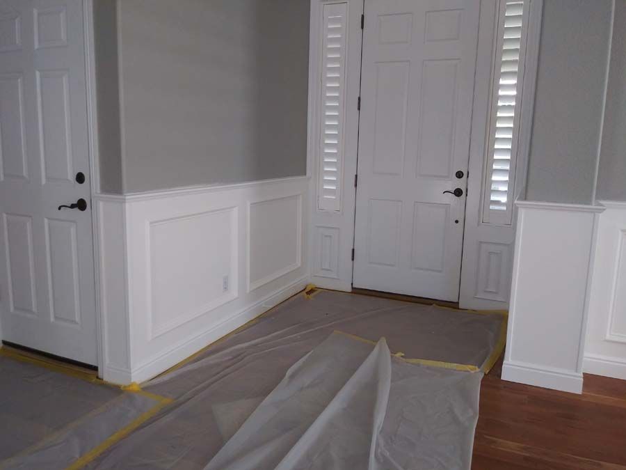 Interior view of an entryway with white trim, gray walls, and a closed white door.