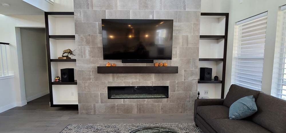 Living room with stone fireplace, TV, built-in shelves, sofa, and light gray rug.