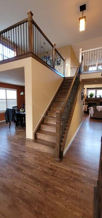 Interior view: staircase with wooden steps and railing, leading up to a second-floor landing. Hardwood floors and neutral walls.