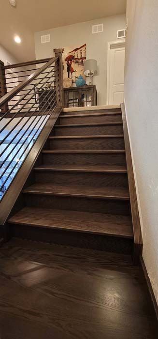 Wooden staircase with a metal railing, leading upwards.