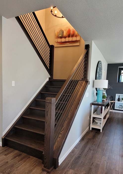 Wooden staircase with dark brown treads and railings, featuring horizontal metal cable balusters.