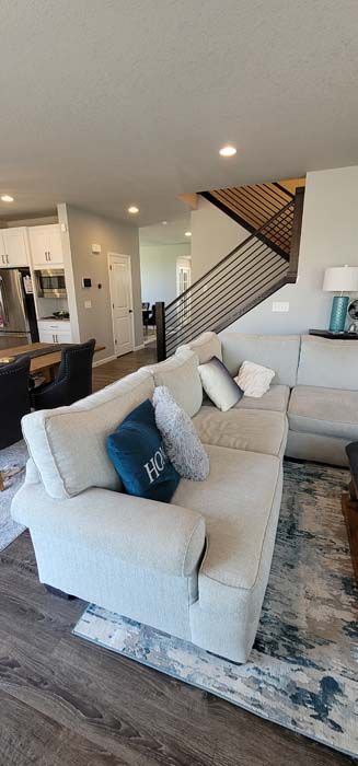 Living room with a sectional sofa, rug, and staircase.