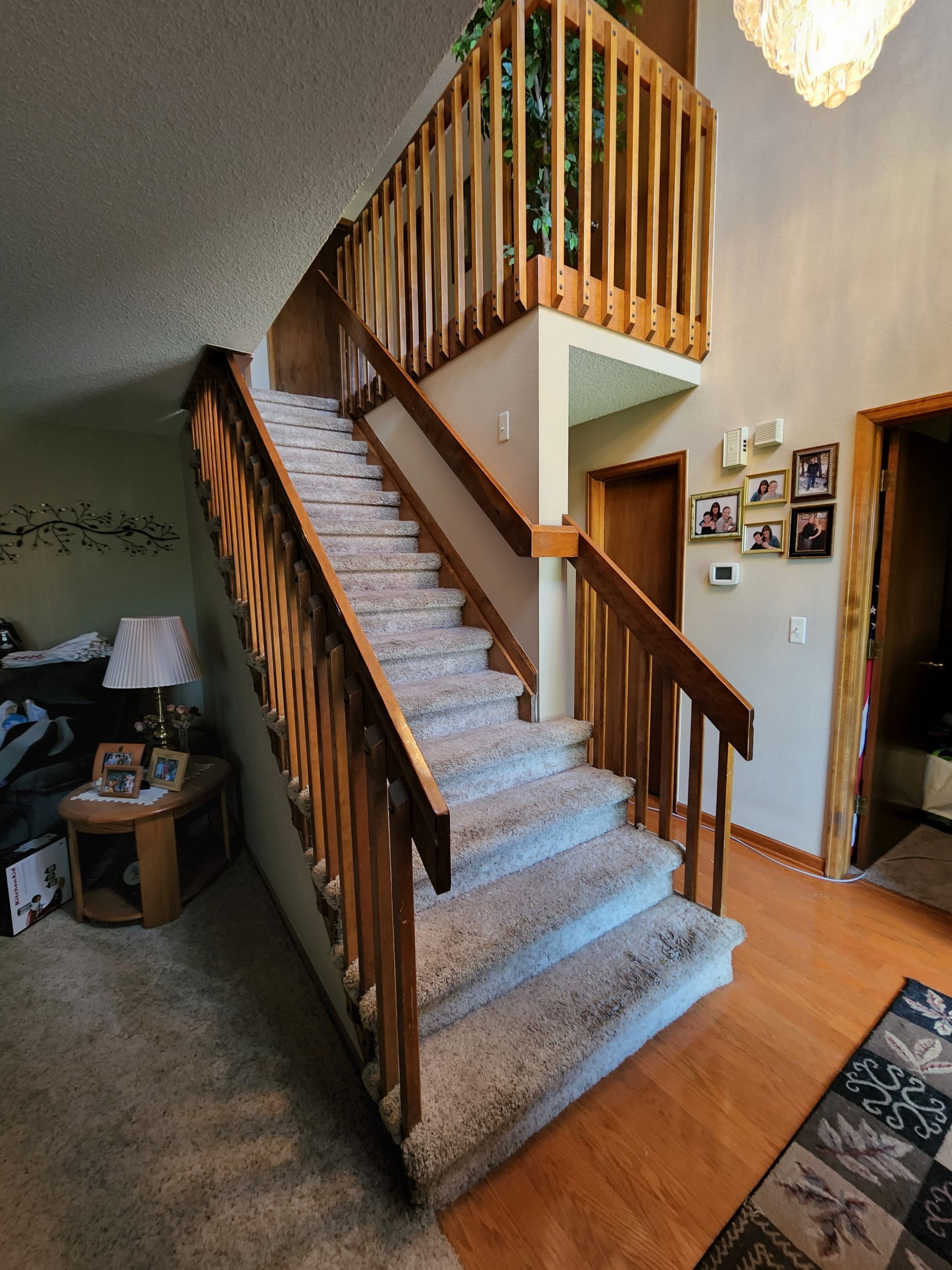 Wooden staircase with carpeted steps leading to a second-floor railing. Light wood floors and trim.