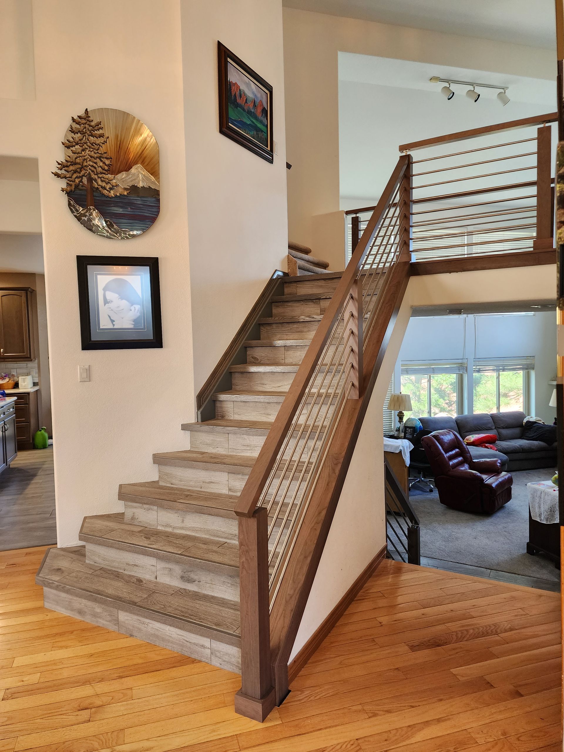 Wooden staircase with dark brown handrails and wire mesh panels, leading to an upper level.