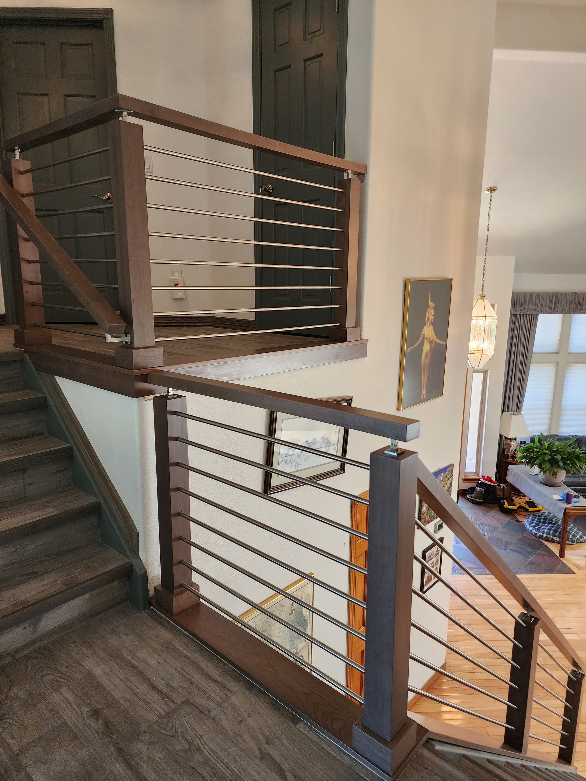 Wooden staircase with dark brown railing and horizontal metal cables.