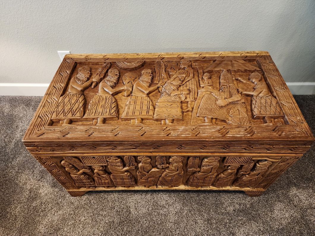 Wooden chest with carved figures on the lid and sides.