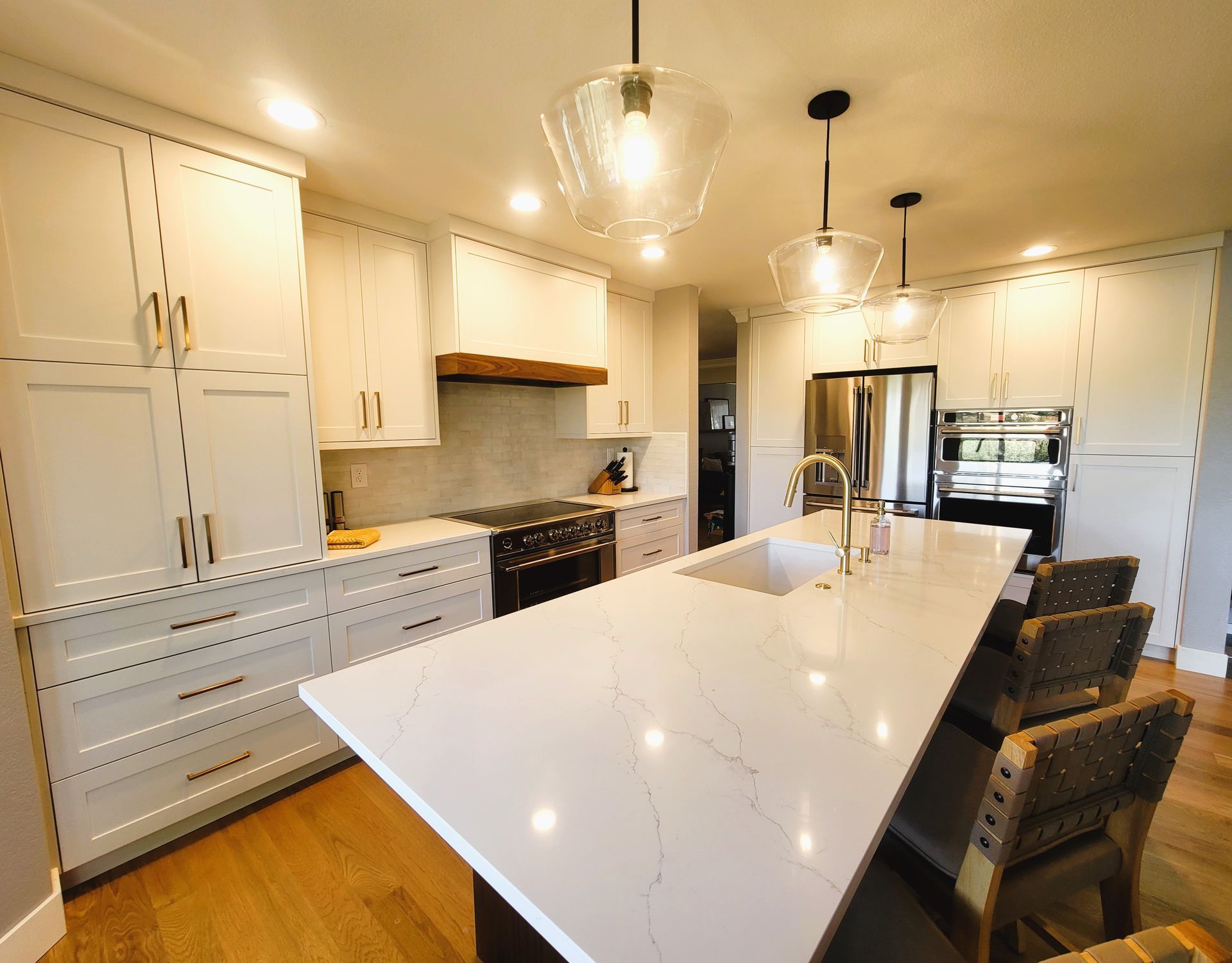 Modern kitchen with white cabinets, island, wooden floor, and pendant lights.
