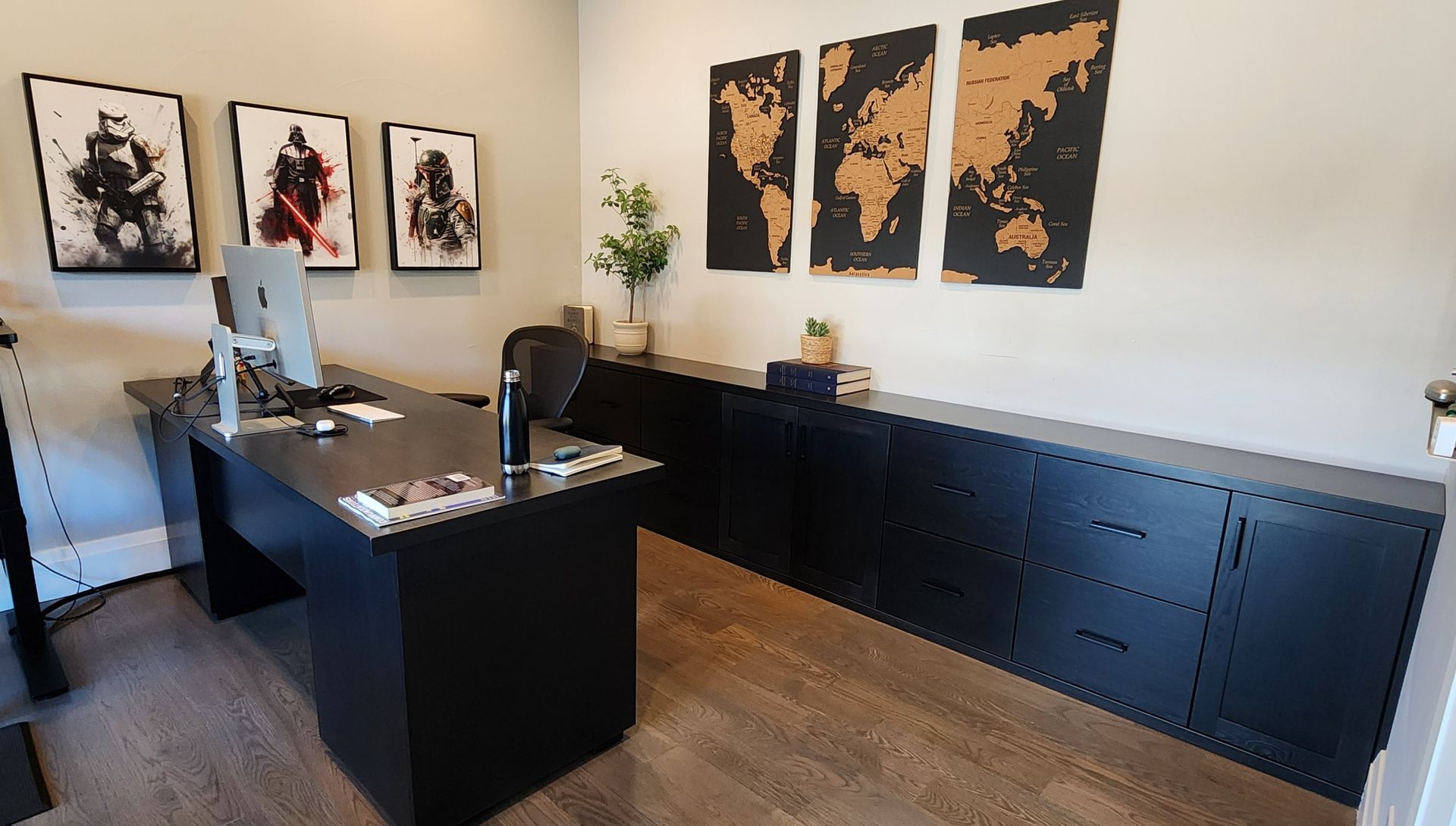 Modern black office with desk, storage, Star Wars art, and world map corkboard.