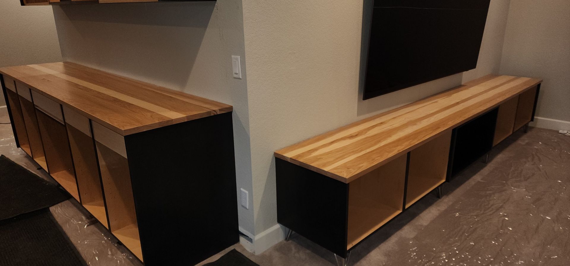 Two custom wood cabinets, black and light wood. One cabinet beneath a wall-mounted TV.