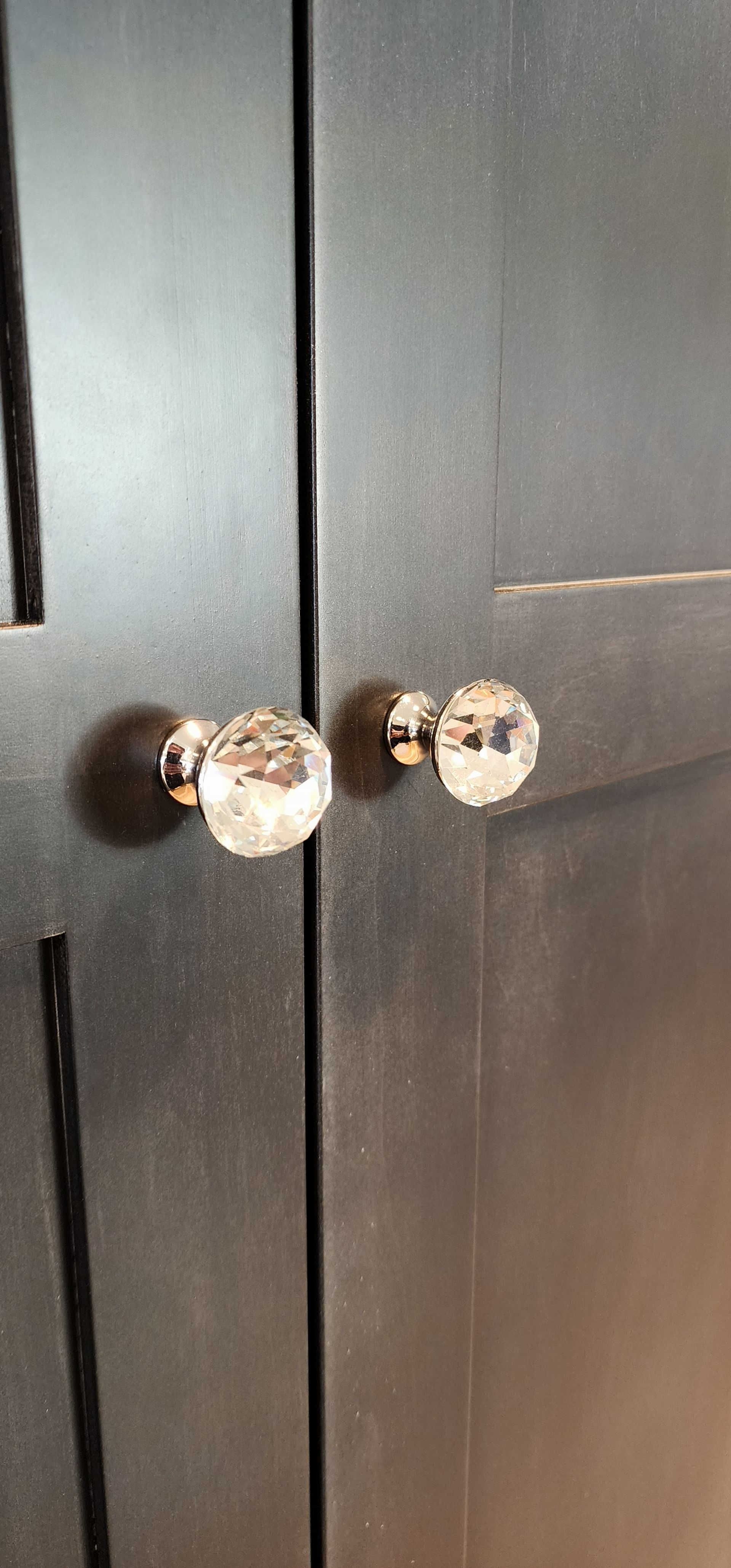 Two dark cabinet doors with crystal knobs.