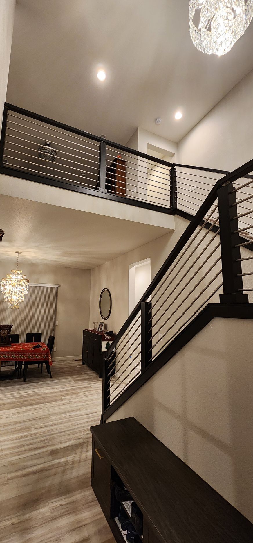 Modern interior with a staircase, black railing, and a second-story landing with dotted panels.