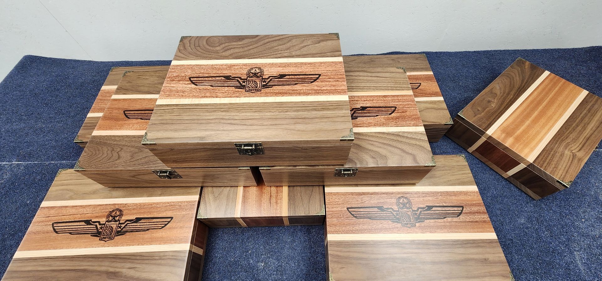 Wooden boxes with inlaid designs and metal clasps, arranged on a blue surface.