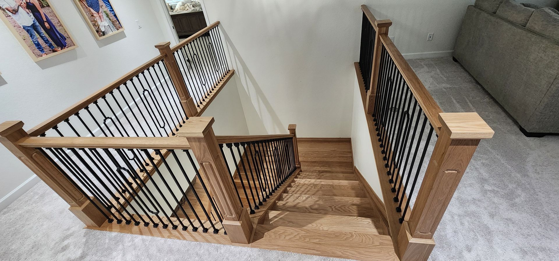 Wooden staircase with black metal railings, carpeted stairs, and light-colored walls.