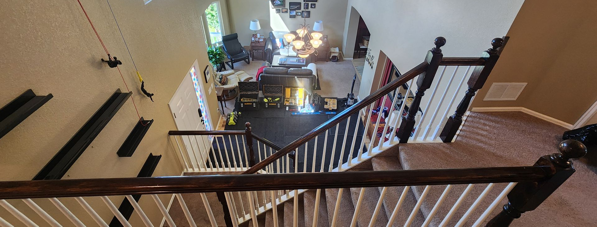 Looking down from a staircase into a two-story living room, a sitting area is visible.