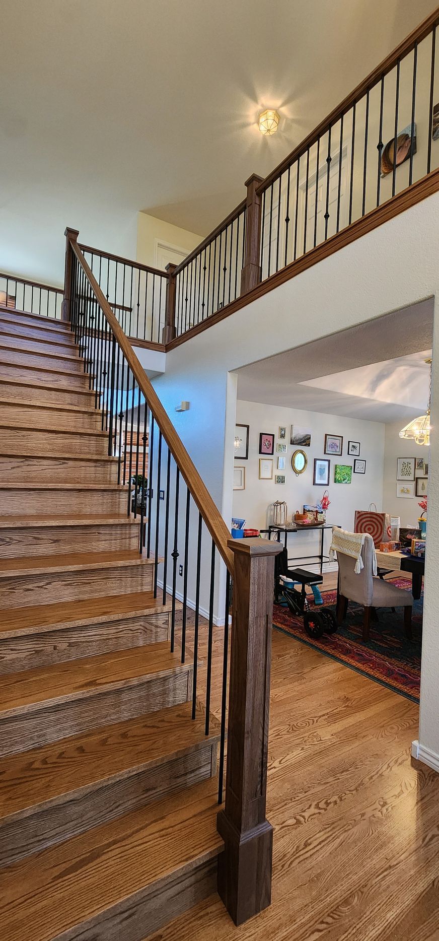 Wooden staircase leading to a second floor balcony, with view of a living room.