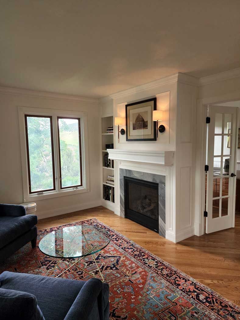 A living room with a fireplace and a wooden mantle.