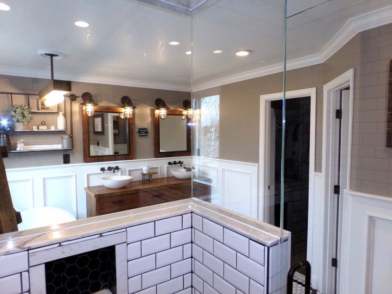 Bathroom with white tile, a wood vanity, and a glass shower enclosure.
