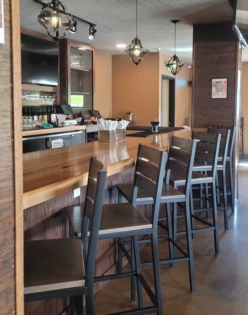 Bar with stools, wood counter, and decorative light fixtures.