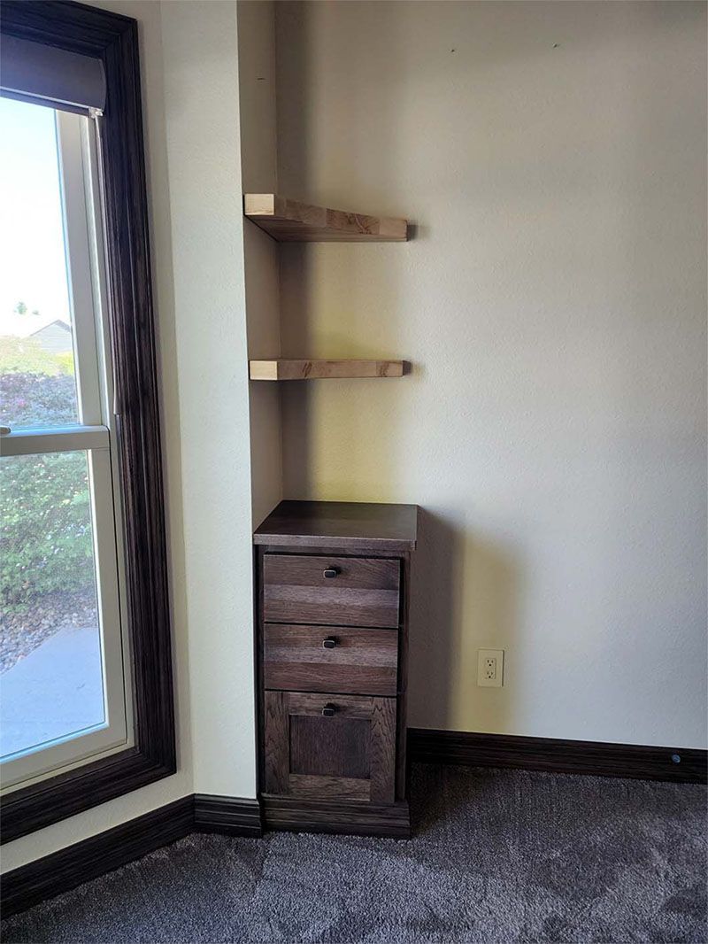 Corner with wooden shelves and a dark cabinet. Window is on the left.