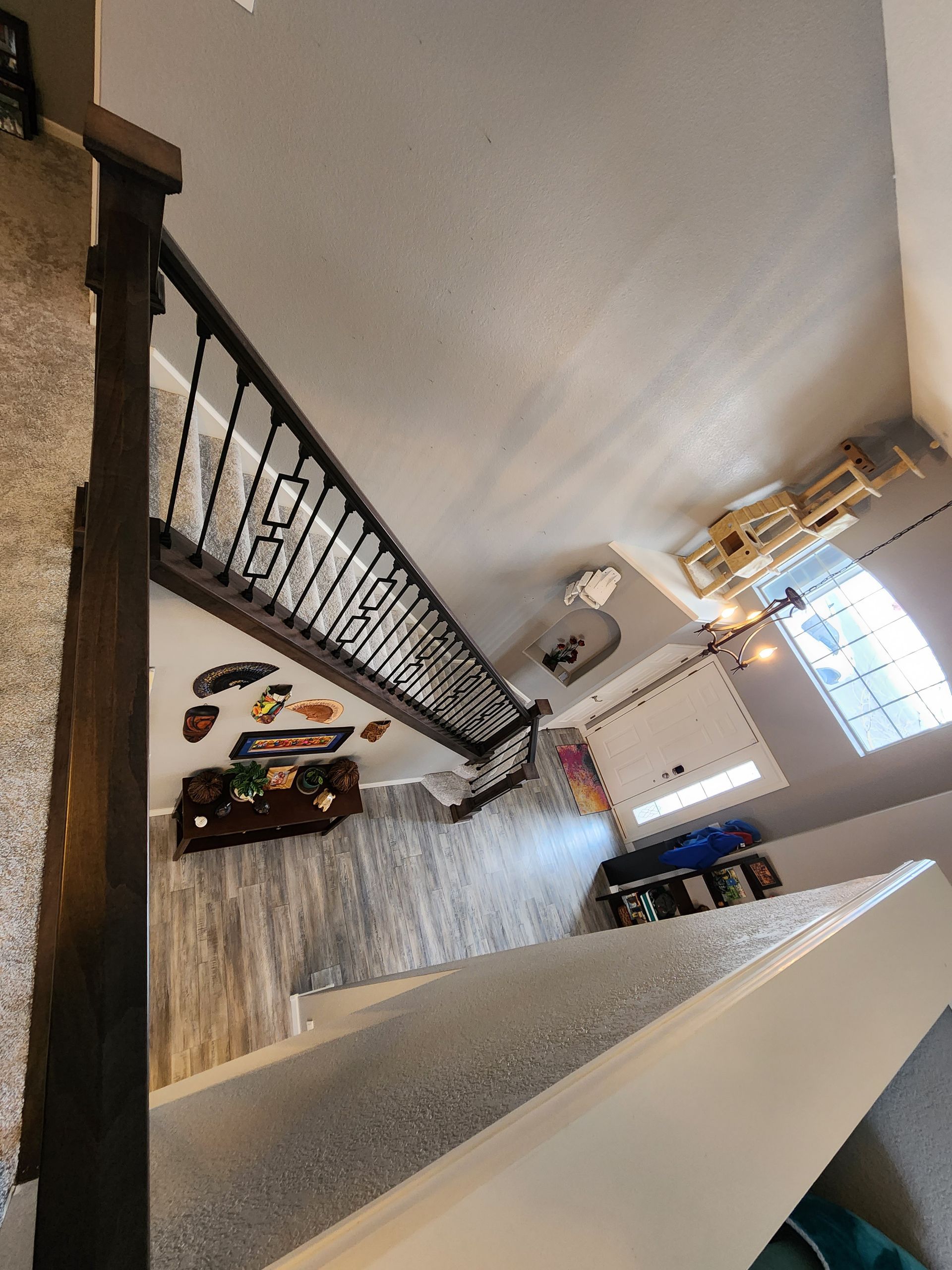 Staircase with dark wood railing and wrought iron balusters; leading to a light-filled room.