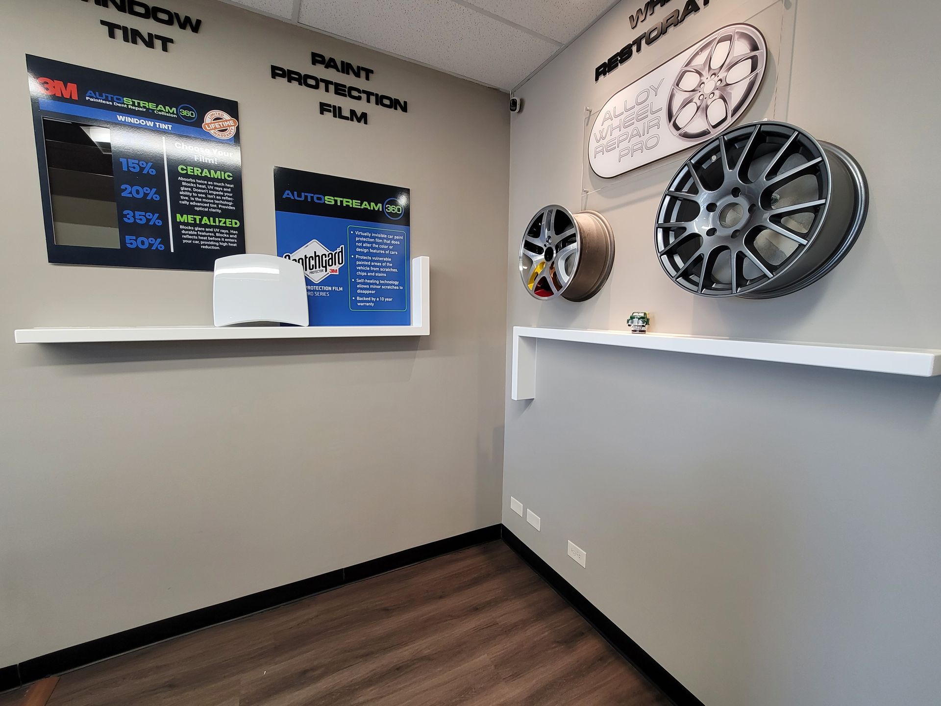Interior of a shop with displays for window tint, paint protection film, and wheels mounted on the wall.
