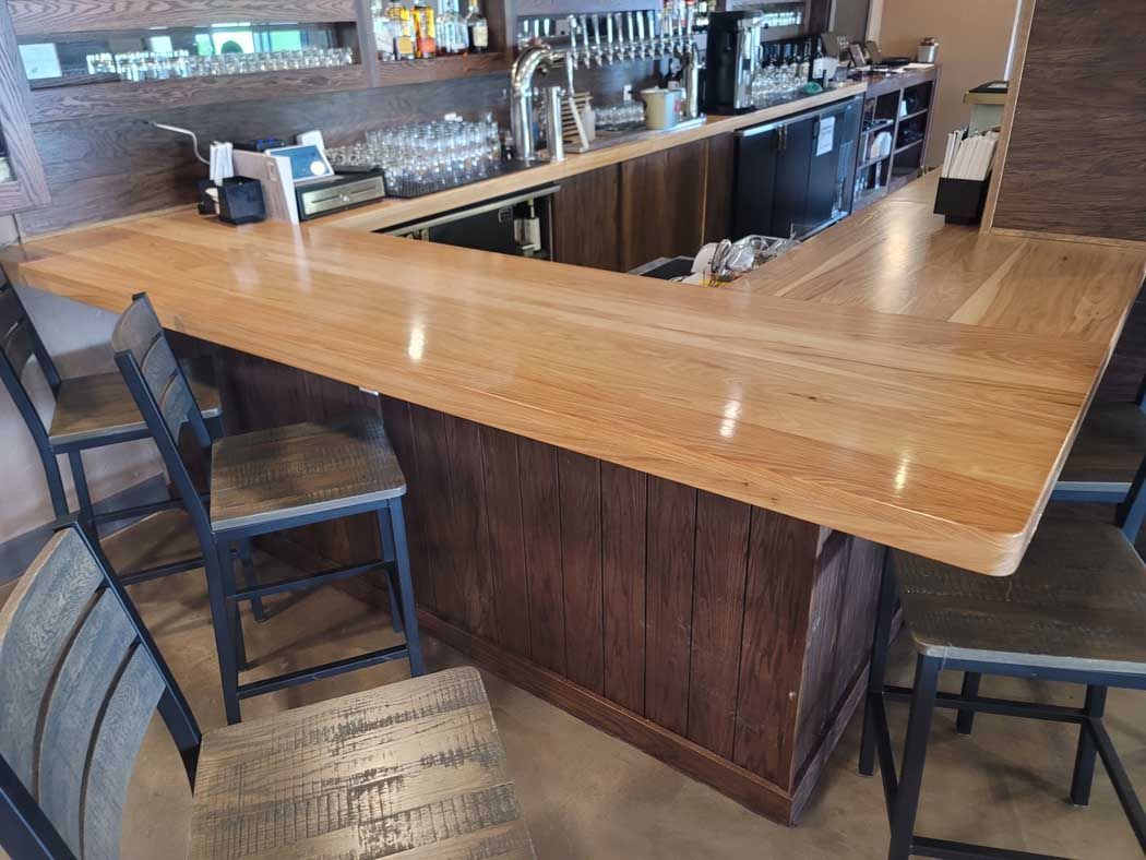Wooden bar with stools in a restaurant setting.