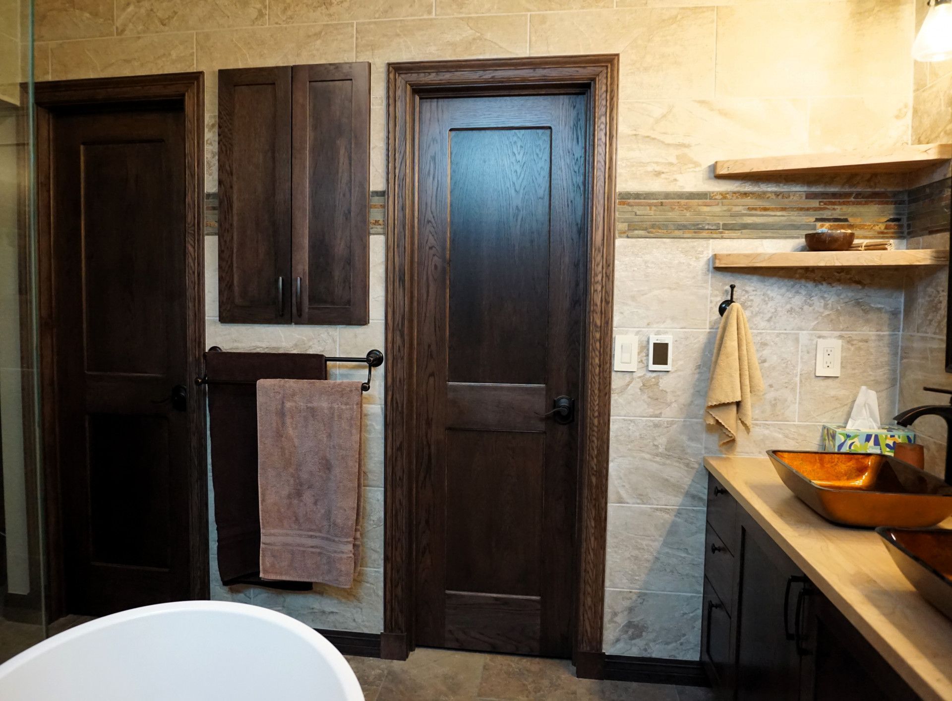 Bathroom with dark wood doors, cabinetry, and tile. A towel hangs on a rack.