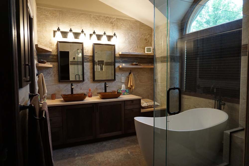Bathroom with a freestanding tub, dual vanities with vessel sinks, and stone tile walls.