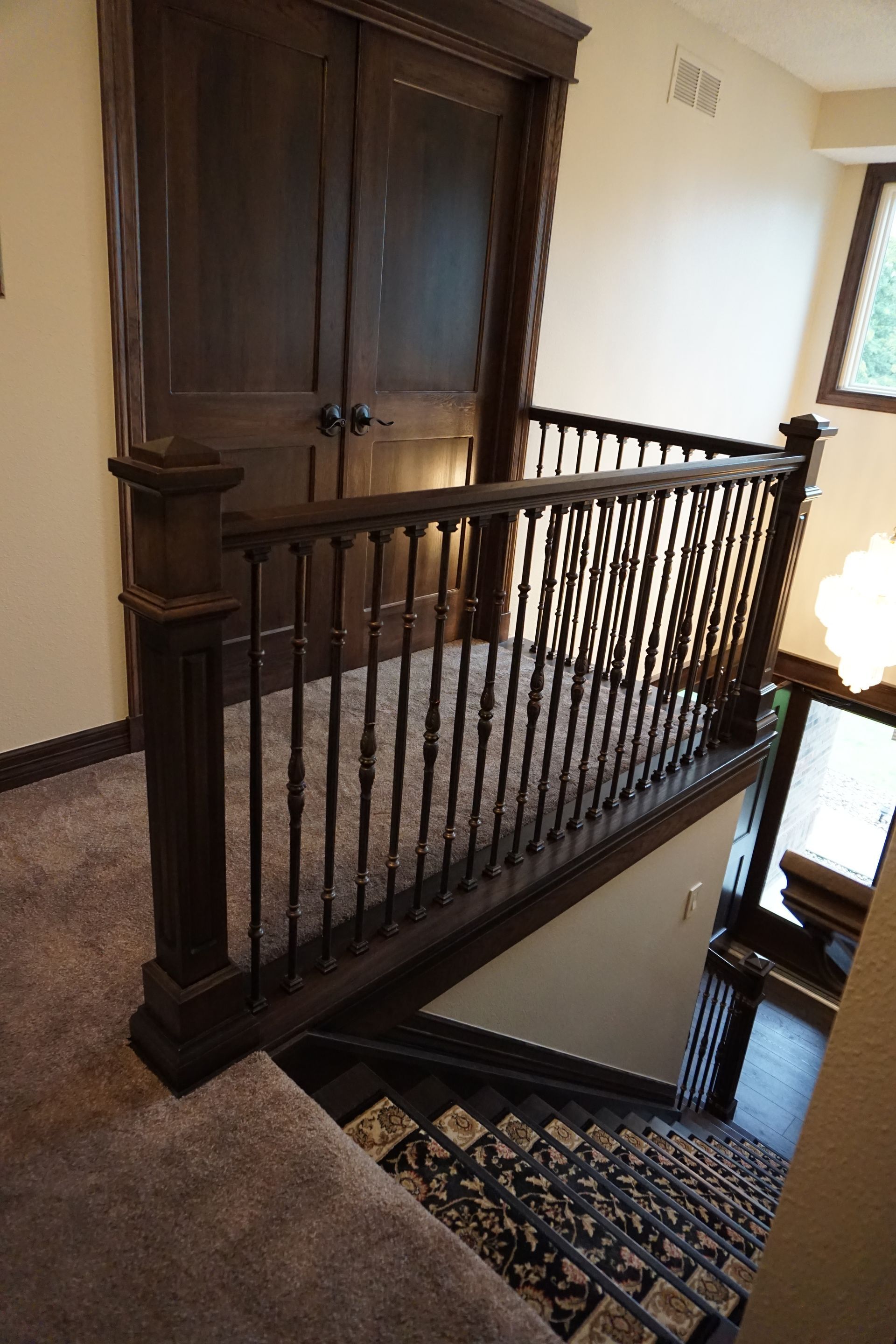 Dark wood staircase with carpet, railing, and a closed door in the background.