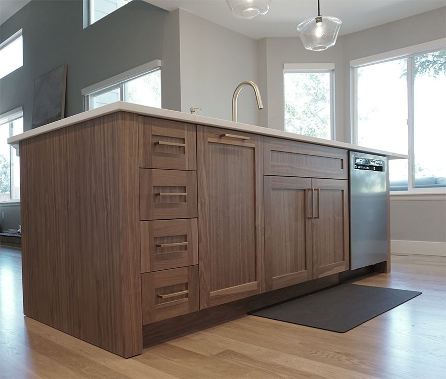 Kitchen island with wooden cabinets, gold faucet, and stainless steel dishwasher.
