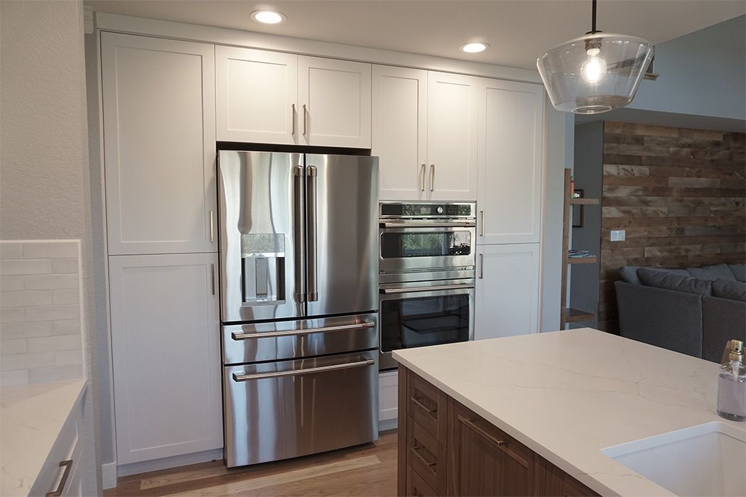 Stainless steel fridge and oven in a bright white kitchen with an island.