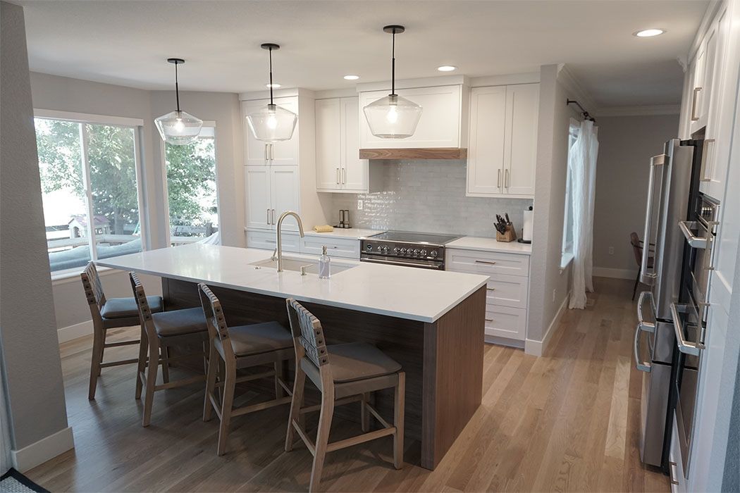 Modern kitchen with white cabinets, island with stools, and pendant lights.