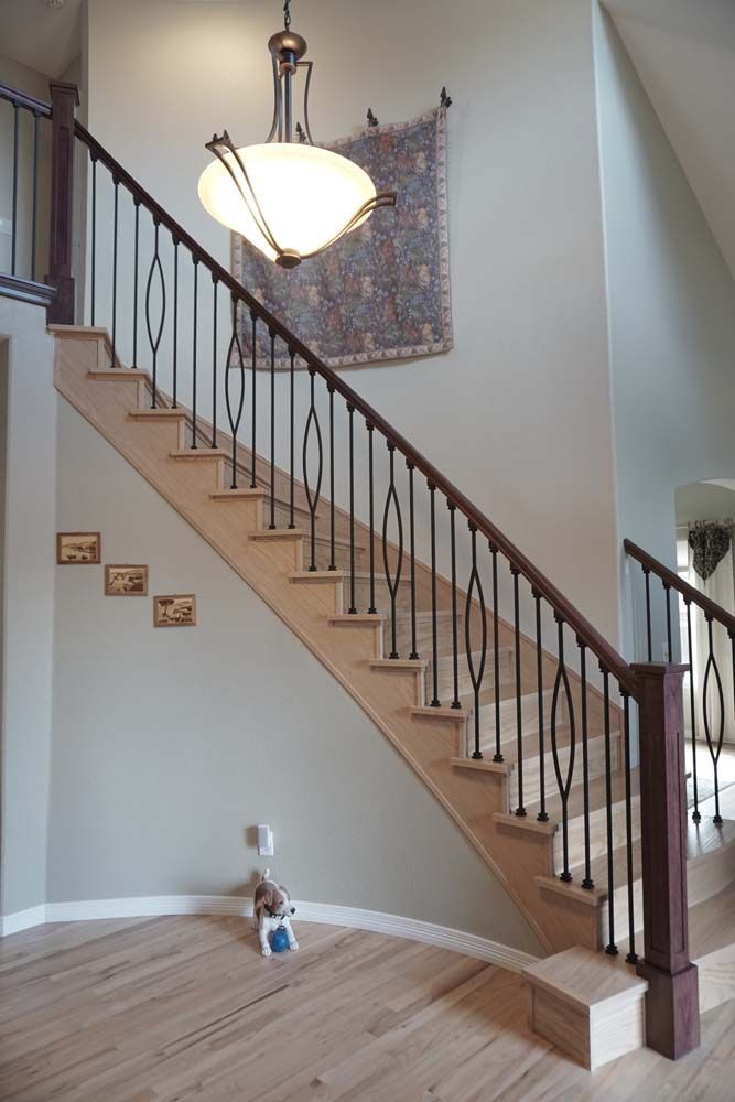 A staircase with light wood steps, dark metal railings, and a tapestry on the wall.