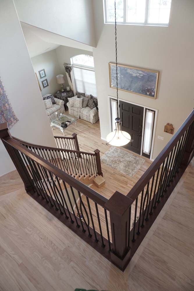View from a staircase landing into a living room and entryway. Hardwood floors, dark railing.