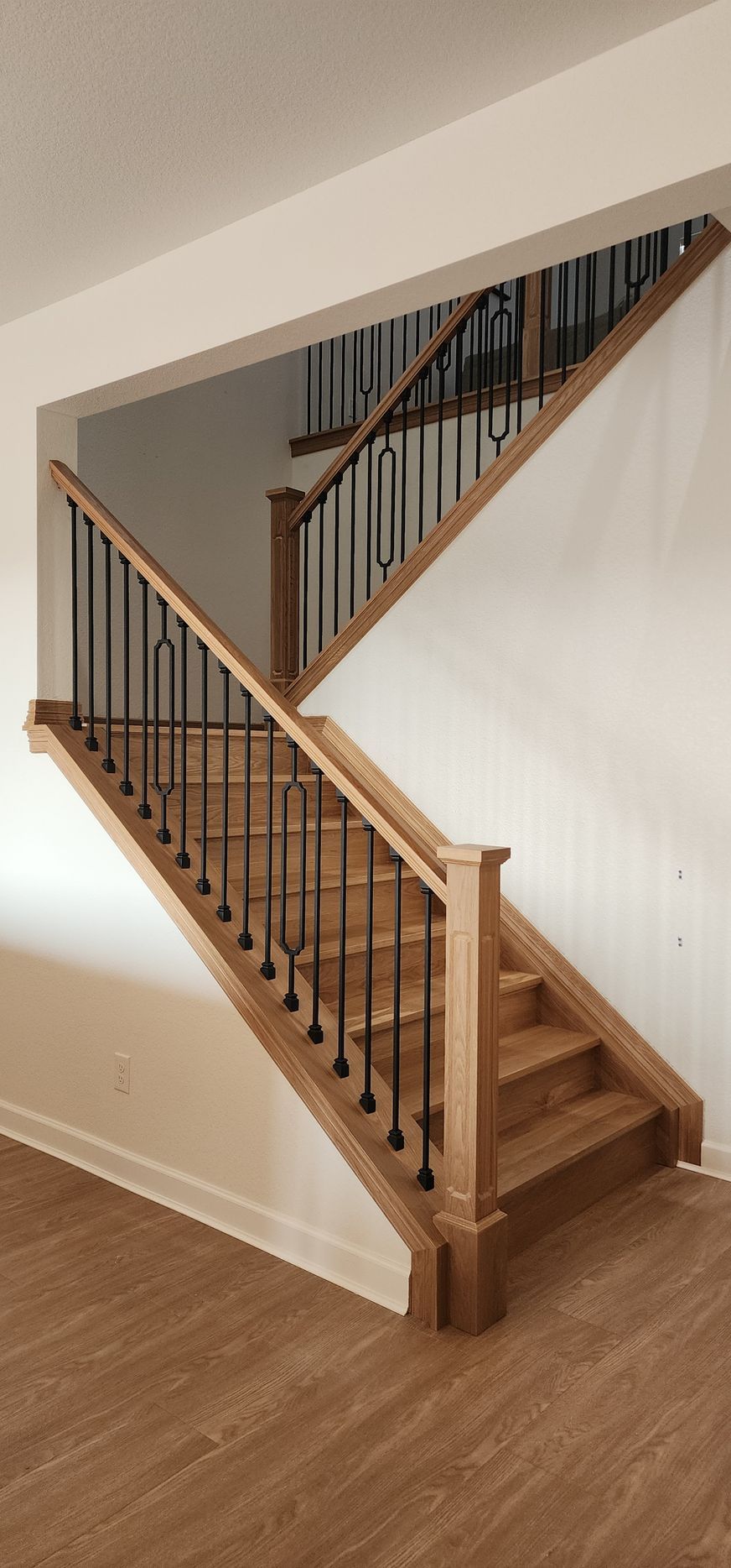 Wooden staircase with black metal railings in a home.