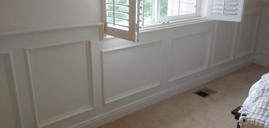 White paneled wall with a window, white shutters, and beige carpet.