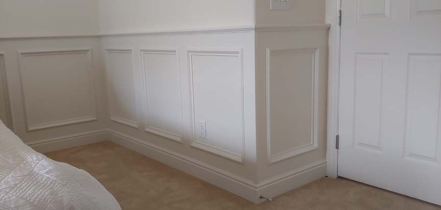 White paneled walls and door in a room with a bed and carpet.