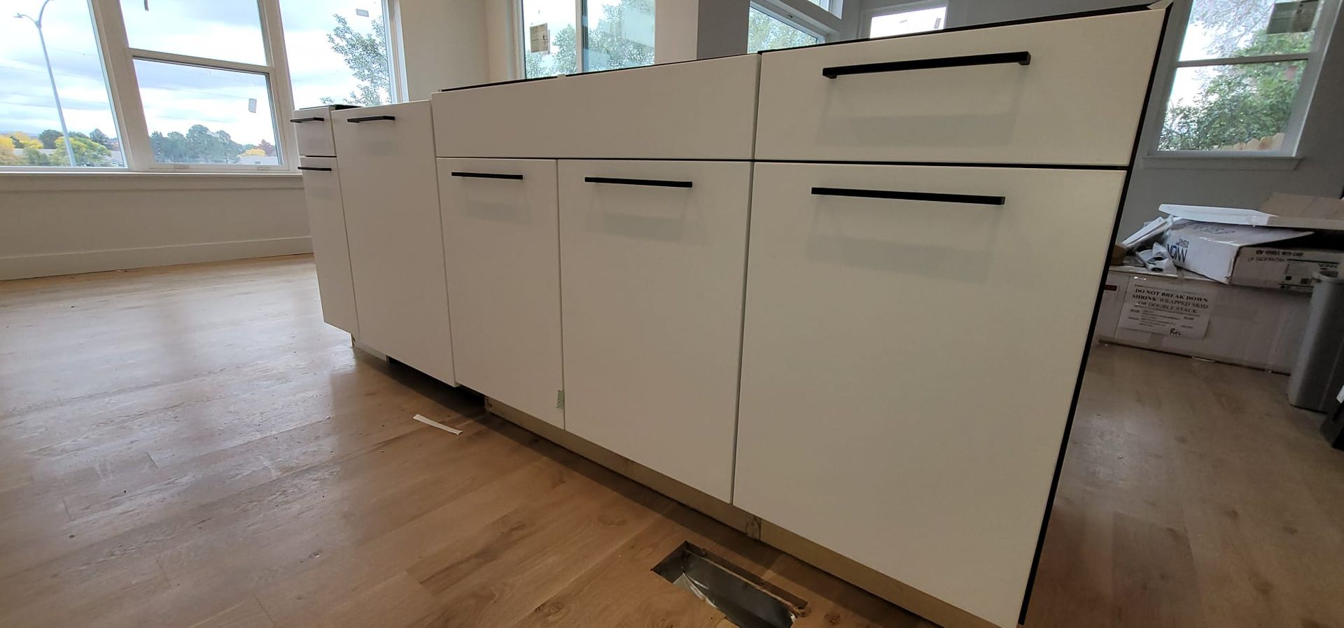 White kitchen cabinets with black hardware and a wooden floor.