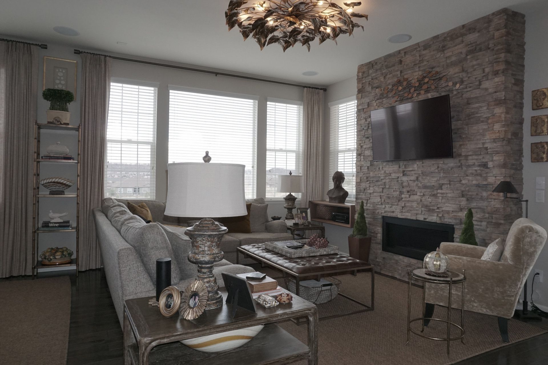 Living room with a stone fireplace, sofa, and large windows.