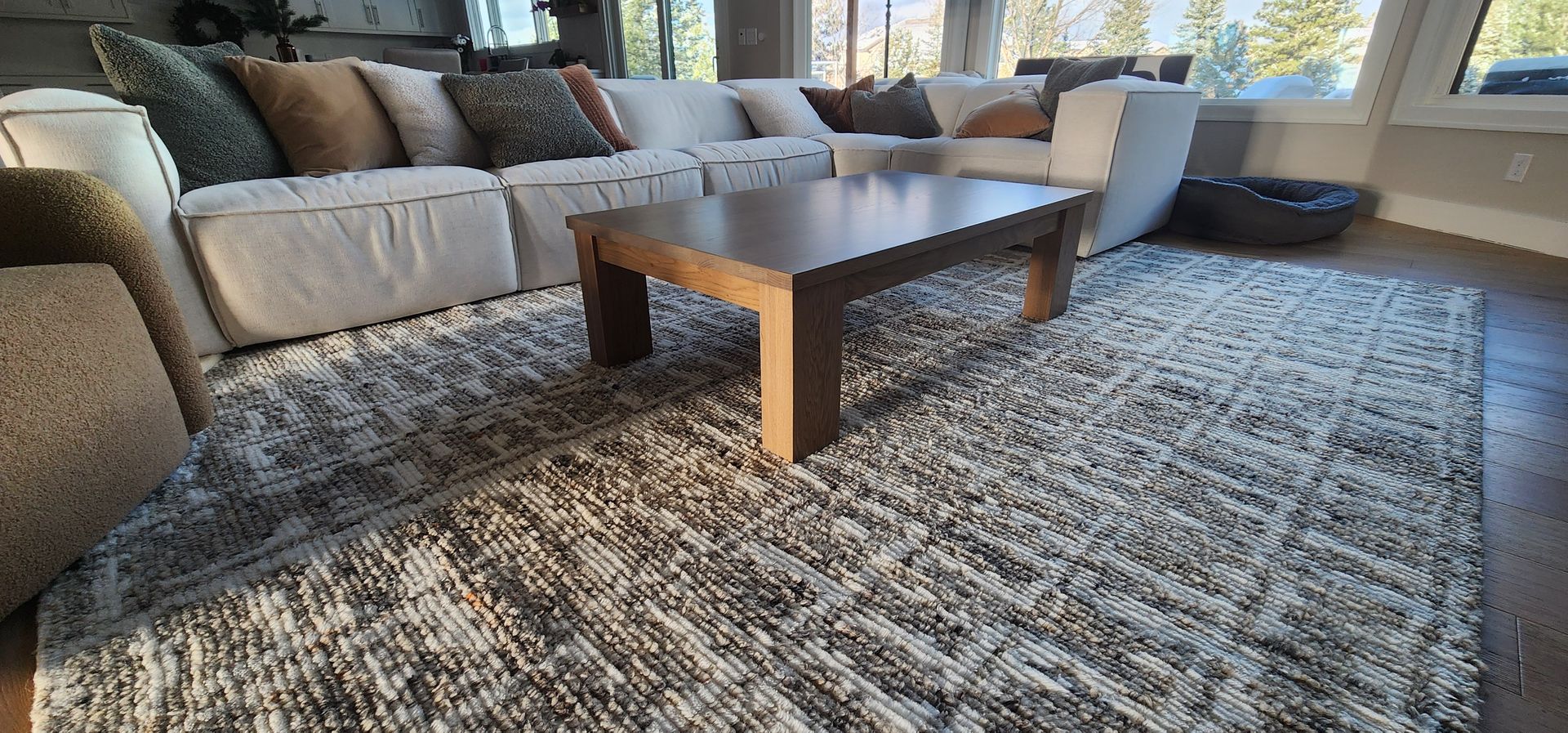 Living room with a large white sectional sofa, brown coffee table, and patterned rug.