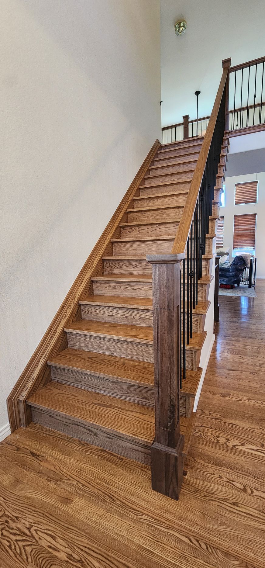 Wooden staircase with dark brown railing and light brown stairs in a house.
