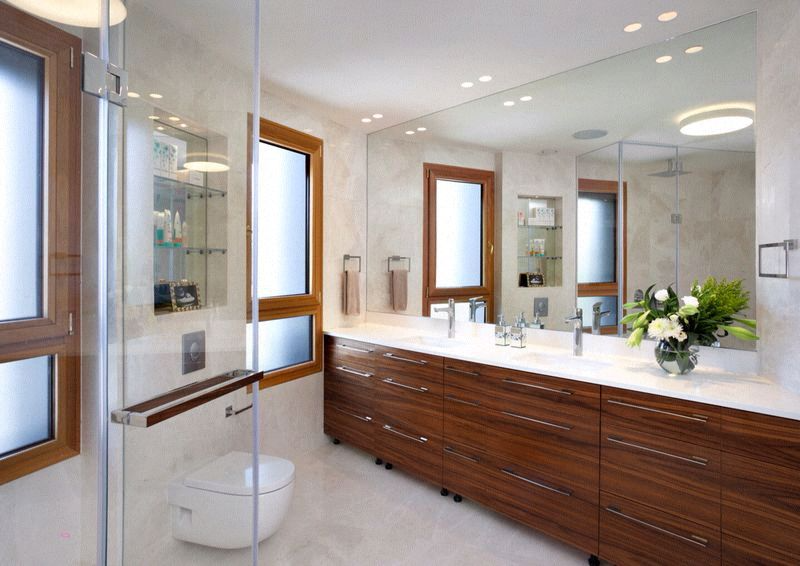 Modern bathroom with wood vanity, large mirror, and glass shower enclosure.