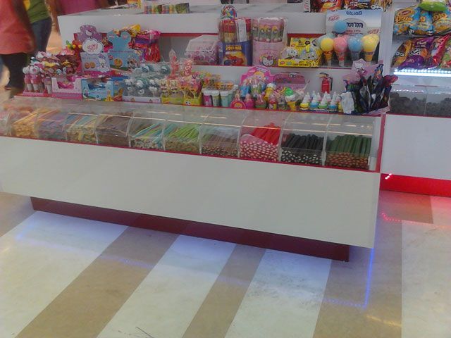 Candy store display with various candies in bins and shelves of treats.