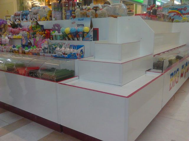 White toy store display with tiered shelves, glass cases, and various colorful toys.