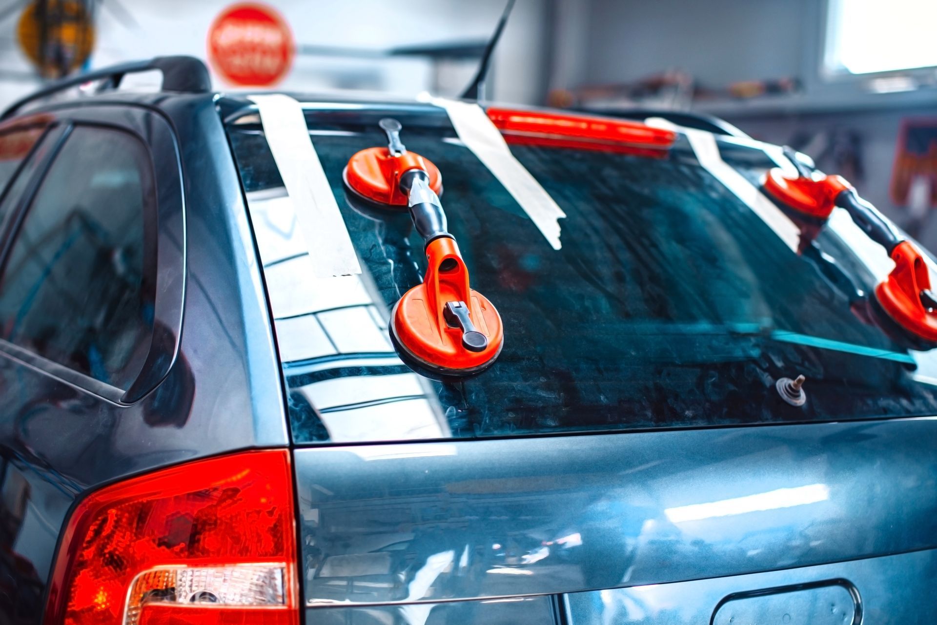 Blue car with orange suction cups attached to the roof and rear window in a garage-like setting Blue car with orange suction cups attached to the roof and rear window in a garage-like setting