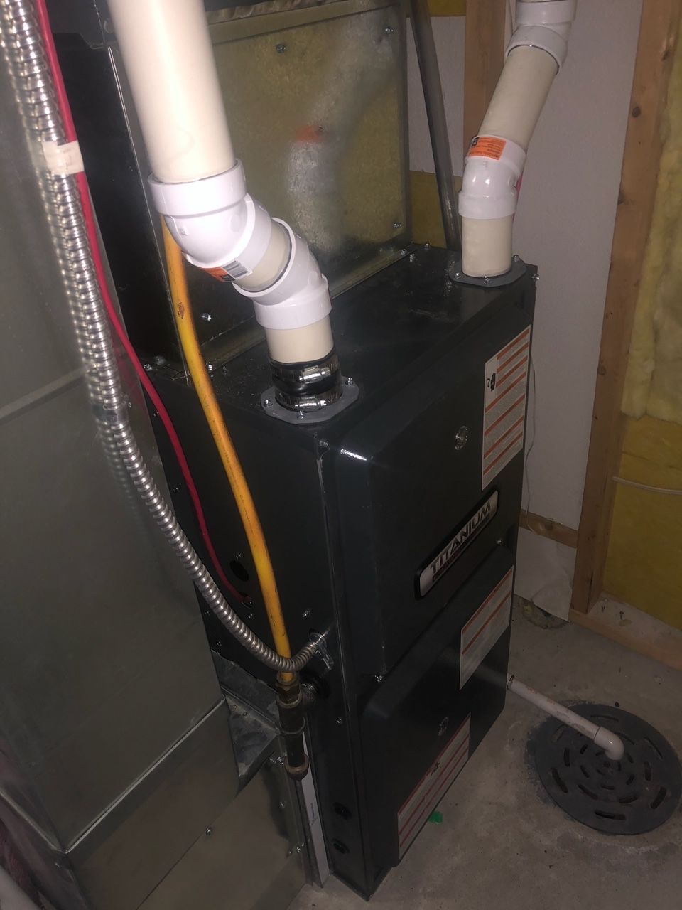 A close up of a furnace in a room with pipes coming out of it.